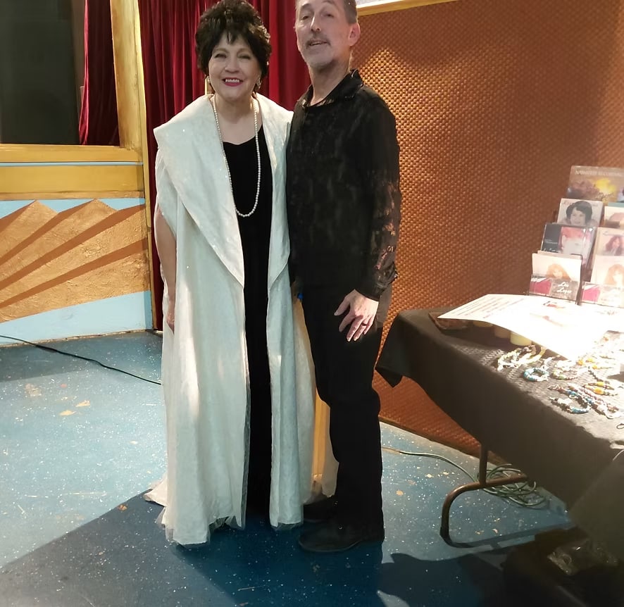 George with Miss Lisa, in a white gown, beside the merch table