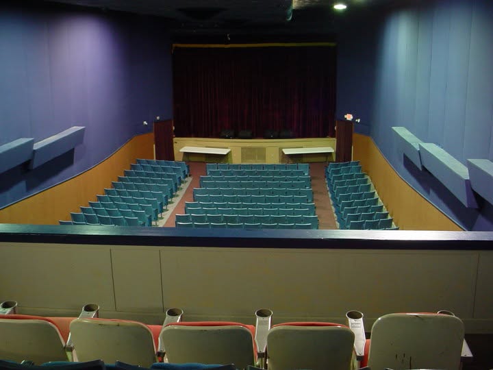 The LanTex house from the balcony: rows of blue seats down to the stage and its red curtain