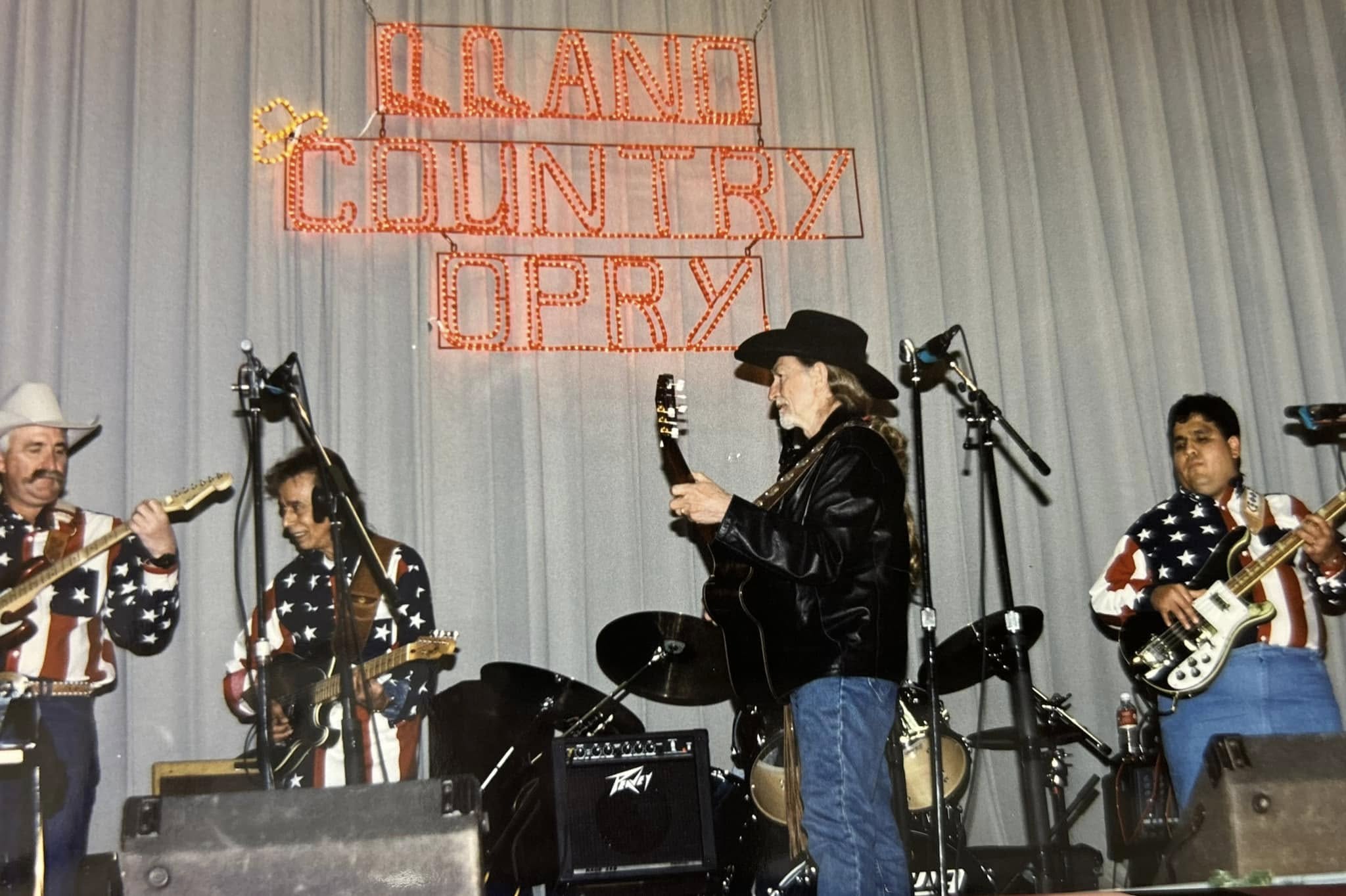 The Opry band in flag shirts playing under the lit Llano Country Opry sign